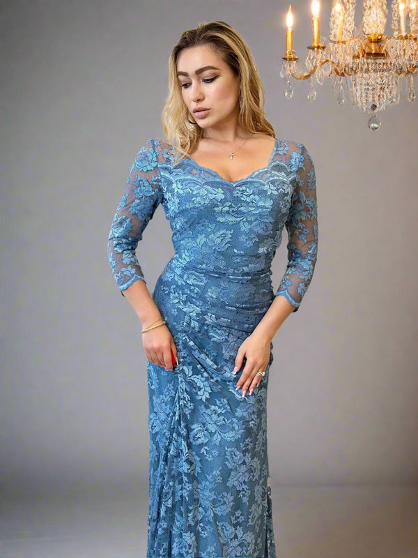 A woman wearing a blue, floral lace long dress with 3/4 sleeves and a V-neck neckline.
