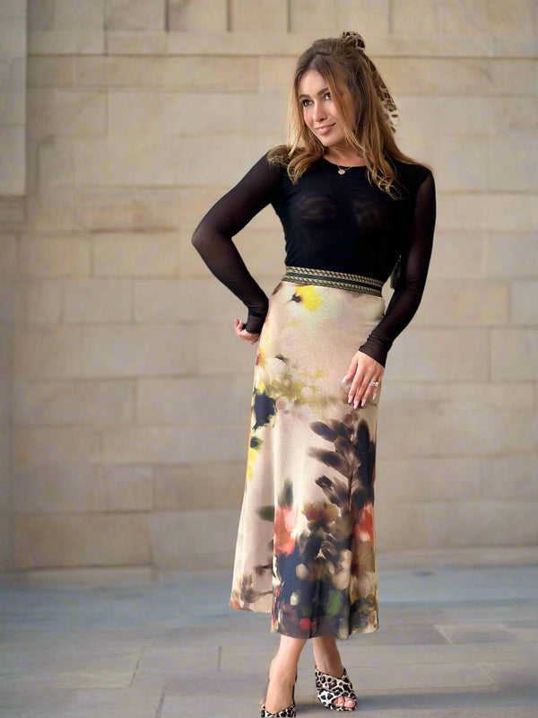 Woman in a living room wearing a black top and colorful skirt.