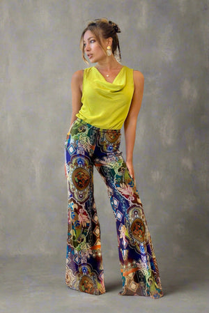 Woman wearing a bright yellow top and colorful patterned pants in a living room.