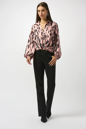 Woman wearing a pink leopard print blouse and black pants on a white background