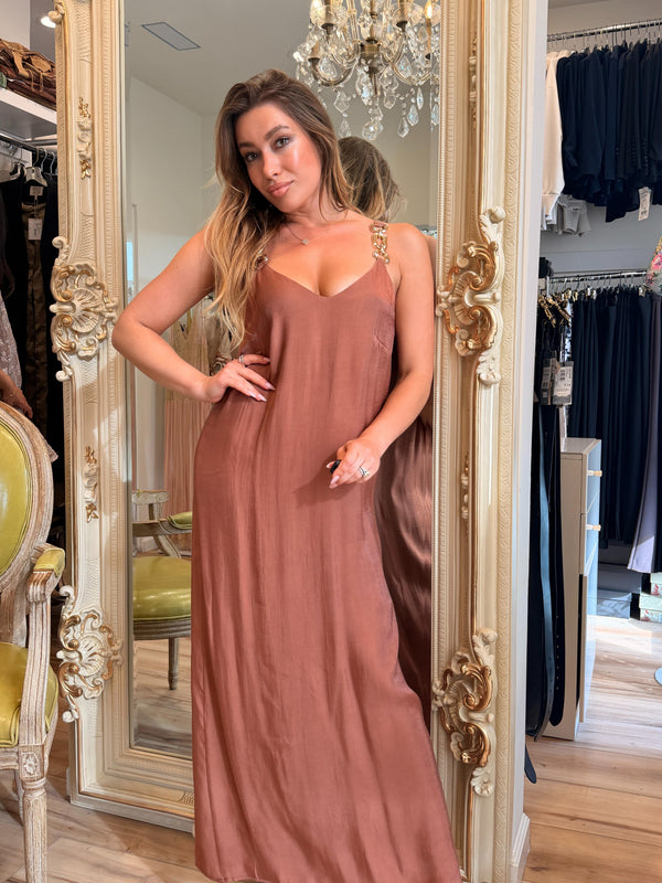 Woman in a brown dress standing in front of a mirror in a store.