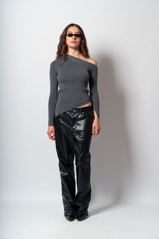 Person wearing a gray off-shoulder top and black leather pants on a white background