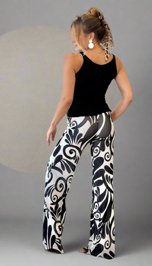 Woman wearing black tank top and patterned pants in a living room.