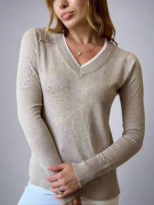 Woman wearing a beige sweater in an indoor setting